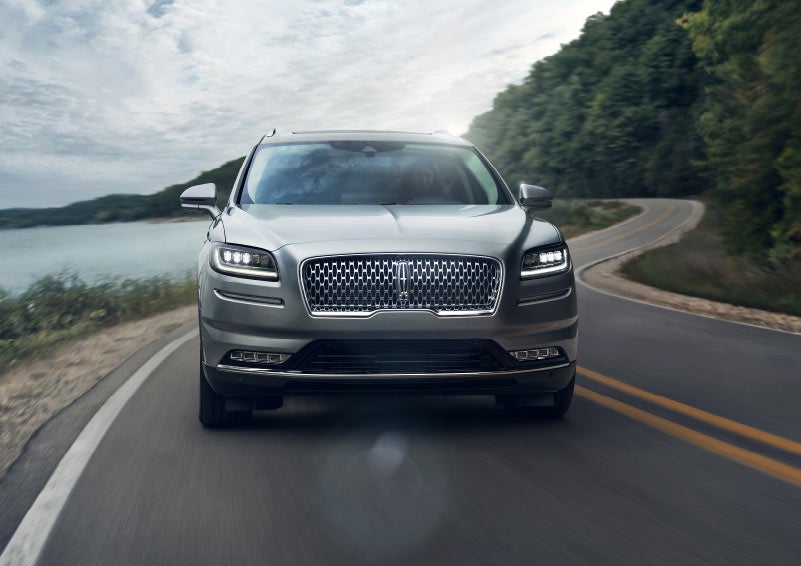 A 2023 Lincoln Nautilus® SUV is shown being driven with its LED headlamps illuminated.