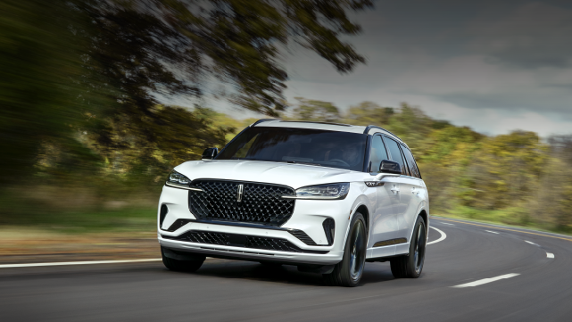 A white 2025 Lincoln Aviator® SUV is being driven down a road lined with trees. | Holmes Tuttle Lincoln in Tucson AZ