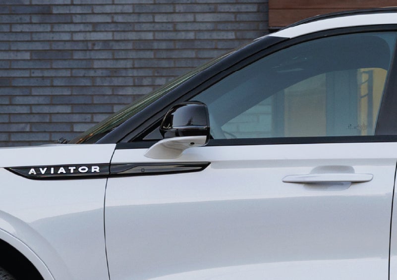 The driver’s side door and fender badging of a white 2026 Lincoln Aviator® SUV are showcased. | Holmes Tuttle Lincoln in Tucson AZ