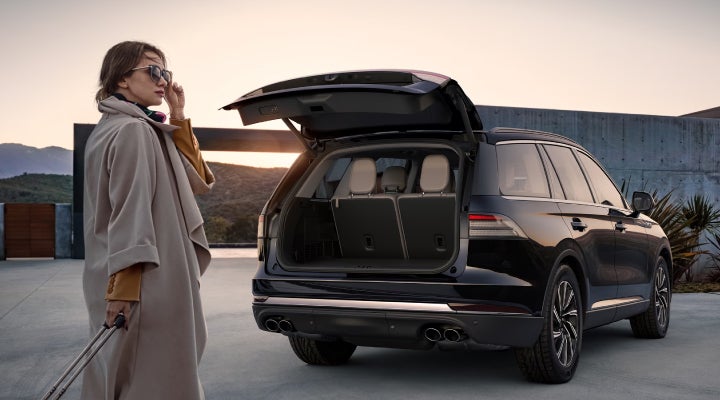 A woman approaches a 2026 Lincoln Aviator® SUV with its rear liftgate open. | Holmes Tuttle Lincoln in Tucson AZ