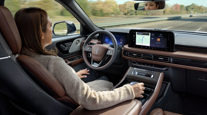A 2026 Lincoln Aviator® SUV is being driven hands-free on a highway near a forest | Holmes Tuttle Lincoln in Tucson AZ