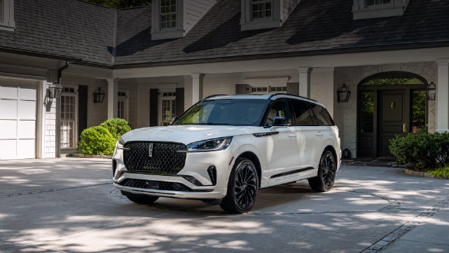 A white 2026 Lincoln Aviator® SUV is parked in the driveway of a luxury home. | Holmes Tuttle Lincoln in Tucson AZ