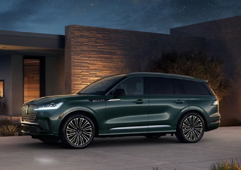 A green 2027 Lincoln Aviator® SUV is parked outside a contemporary home. | Holmes Tuttle Lincoln in Tucson AZ