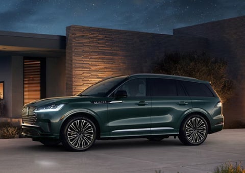 A green 2027 Lincoln Aviator® SUV is parked outside a contemporary home. | Holmes Tuttle Lincoln in Tucson AZ