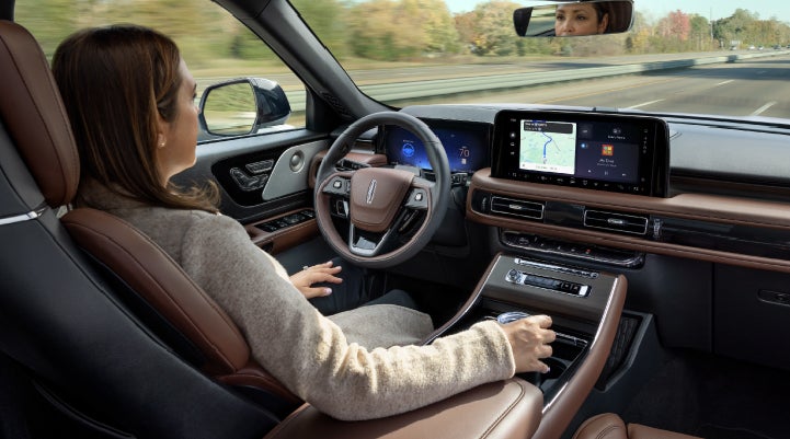 A 2027 Lincoln Aviator® SUV is being driven hands-free on a highway lined with trees. | Holmes Tuttle Lincoln in Tucson AZ