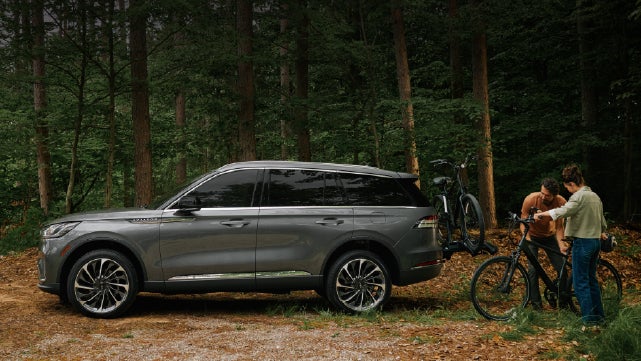 A father and son load e-bikes on a bike rack attached to a 2027 Lincoln Aviator® SUV. | Holmes Tuttle Lincoln in Tucson AZ