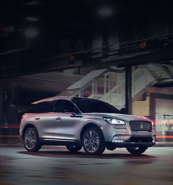 A Lincoln Corsair is shown being driven on a city street at night